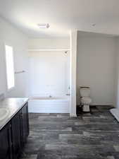 Master bathroom with vanity, shower / tub combination, dark wood-style flooring