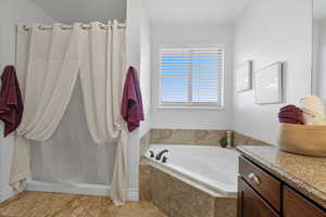 Bathroom with a garden tub, a shower stall, vanity, and light tile patterned floors