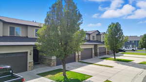 View of front of property featuring stone siding, stucco siding, a shingled roof, and concrete driveway