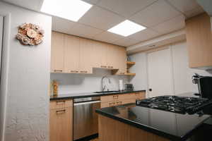 Kitchen with a paneled ceiling, dishwasher, backsplash, light brown cabinets, and open shelves