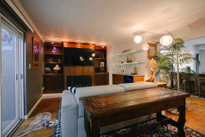 Living room with a fireplace, wood finished floors, and crown molding