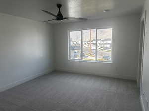 Carpeted empty room with a ceiling fan and a textured ceiling