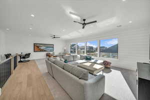 Living area featuring recessed lighting, a ceiling fan, light wood-style floors, and wooden walls
