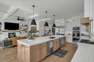 Kitchen featuring pendant lighting, light stone countertops, open floor plan, built in appliances, and beam ceiling