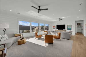 Living room featuring recessed lighting, ceiling fan, light wood finished floors, and wood walls