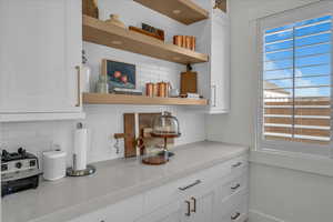 Detailed view of white cabinets, tasteful backsplash, and open shelves