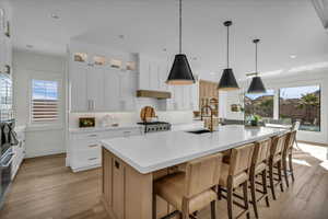 Kitchen with white cabinets, hanging light fixtures, a kitchen bar, and recessed lighting