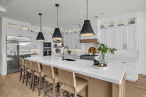 Kitchen with built in appliances, glass insert cabinets, light wood-type flooring, white cabinets, and recessed lighting