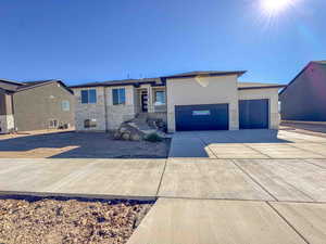 View of front of home featuring stone siding, driveway, and an attached garage