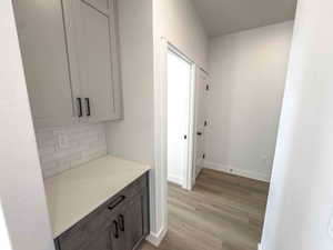 Bar area featuring light wood-type flooring, light stone countertops, and decorative backsplash