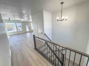 Hall with an upstairs landing, light wood-style floors, recessed lighting, a chandelier, and a textured ceiling