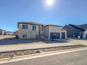 View of front of property with concrete driveway, stone siding, and an attached garage