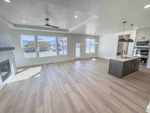 Kitchen featuring open floor plan, a tray ceiling, recessed lighting, healthy amount of natural light, and a kitchen island with sink