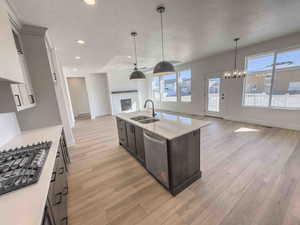 Kitchen with open floor plan, a textured ceiling, hanging light fixtures, appliances with stainless steel finishes, and healthy amount of natural light