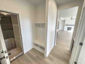 Mudroom featuring light wood finished floors, a fireplace, and ceiling fan