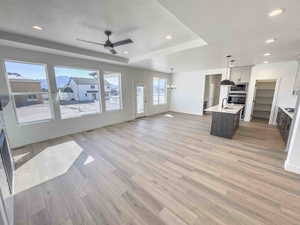 Kitchen featuring open floor plan, a kitchen island with sink, a textured ceiling, ceiling fan, and recessed lighting