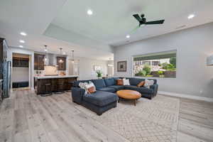 Living room with vaulted ceilings, a glass covered fireplace, recessed lighting, LVP, and natural light