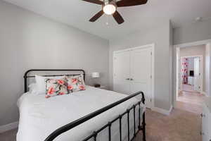 Bedroom with light colored carpet, a ceiling fan, and a closet