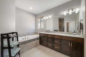 Primary Bathroom featuring an oversized bath, double vanity, recessed lighting, walki-in tile shower, and tile flooring