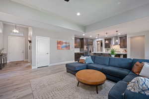 Living room with vaulted ceilings, a glass covered fireplace, recessed lighting, LVP, and natural light