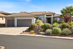 Rambler-style house with stone siding, stucco siding, a tile roof, and 3-car garage