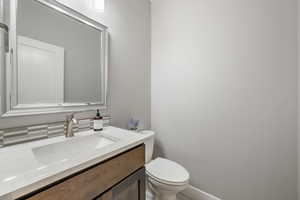 Half bathroom featuring vanity and toilet