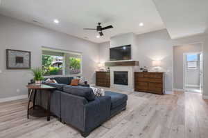 Living room with vaulted ceilings, a glass covered fireplace, recessed lighting, LVP, and natural light