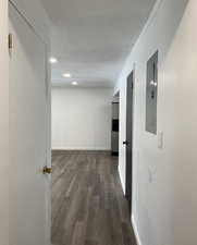 Hallway featuring dark wood-style floors, a textured ceiling, electric panel, recessed lighting, and crown molding