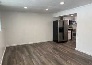 Unfurnished living room with a textured ceiling, dark wood-type flooring, recessed lighting, and crown molding