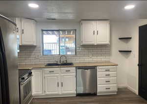 Kitchen featuring recessed lighting, appliances with stainless steel finishes, white cabinetry, and dark wood finished floors