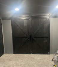 Detailed view of a barn door, carpet floors, and recessed lighting