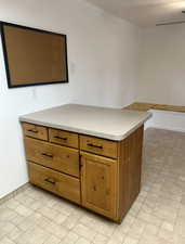 Kitchen with brown cabinetry, light countertops, and ceiling fan