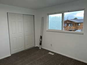 Unfurnished bedroom with dark carpet and a closet