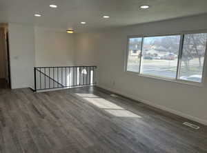 Empty room with recessed lighting and dark wood-style floors