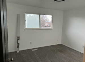 Spare room with dark carpet and baseboards