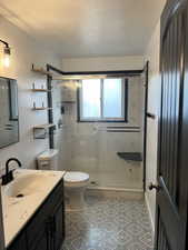 Full bath with a marble finish shower, vanity, and a textured ceiling