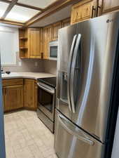 Kitchen featuring stainless steel appliances, brown cabinetry, and open shelves