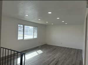 Spare room featuring dark wood-type flooring, recessed lighting, and a textured ceiling