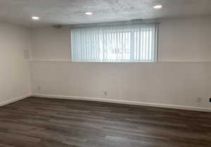 Unfurnished room featuring a textured ceiling, dark wood-type flooring, and recessed lighting