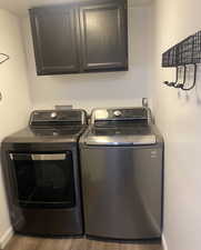 Laundry room featuring cabinet space, washer and clothes dryer, and wood finished floors