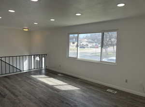 Empty room featuring recessed lighting, dark wood finished floors, and a textured ceiling