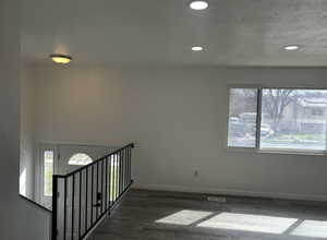 Spare room with plenty of natural light, recessed lighting, dark wood-style flooring, and a textured ceiling