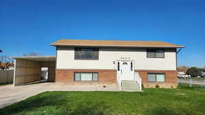 Back of house featuring brick siding, driveway, and an attached carport