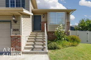 View of exterior entry with brick siding, a garage, and a gate