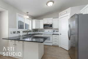 Kitchen featuring pendant lighting, stainless steel appliances, a peninsula, tasteful backsplash, and vaulted ceiling