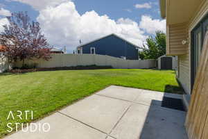 Fenced backyard with a storage unit and a patio