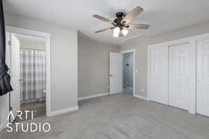 Unfurnished bedroom featuring light carpet, ceiling fan, attic access, a closet, and ensuite bath