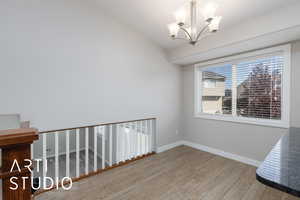 Unfurnished dining area with light wood-style floors, a chandelier, and vaulted ceiling