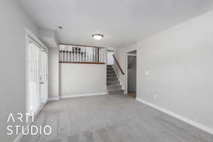 Unfurnished living room featuring carpet flooring and stairs