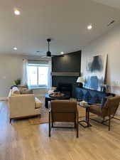 Living room with a large fireplace, light wood finished floors, and recessed lighting
